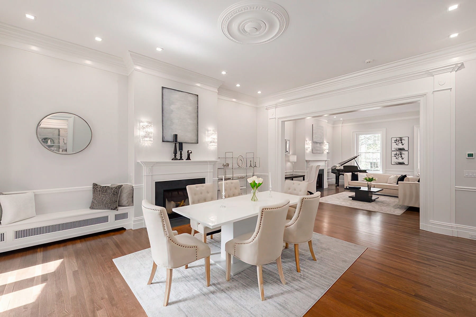Open dining and living rooms with fireplaces, crown molding, custom seating, and wood floors at the Chestnut Street Residence in Boston.