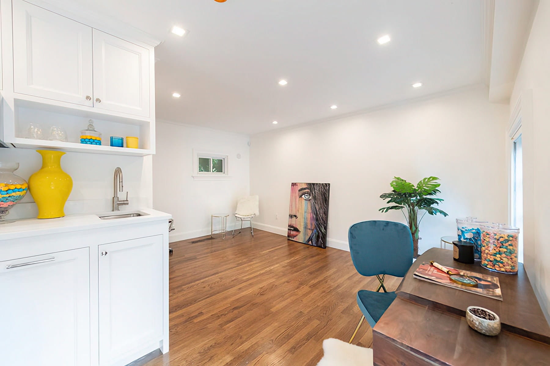 Home office with white built-in cabinetry, a wet bar, wood flooring, and contemporary artwork at the Chestnut Street Residence in Boston.