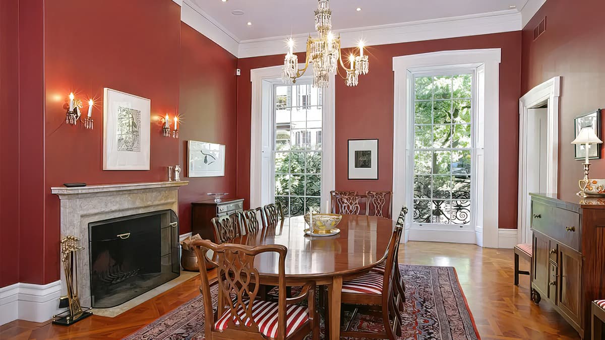 Dining room at the Louisburg Square Townhouse in Boston with historic fireplace, tall windows, red walls, and traditional architectural detailing