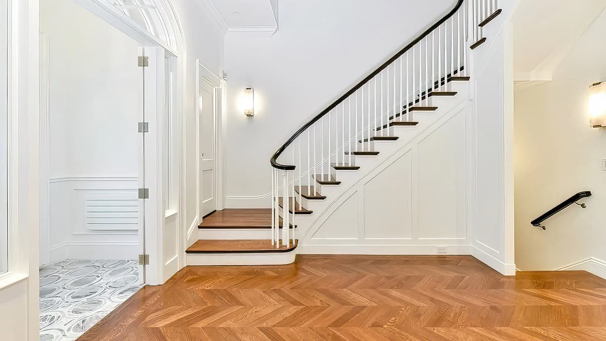 Renovated stair hall at the Mount Vernon Place Townhouse in Boston with custom millwork, herringbone wood flooring, and a curved staircase
