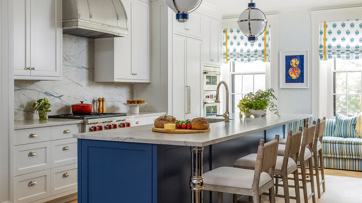 Renovated kitchen at the Myrtle Street Townhouse in Boston with custom cabinetry, blue island, marble surfaces, and pendant lighting